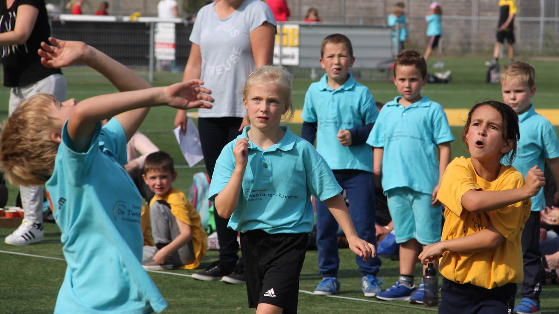 Kinderen spelen samen korfbal op het kunstgrasveld