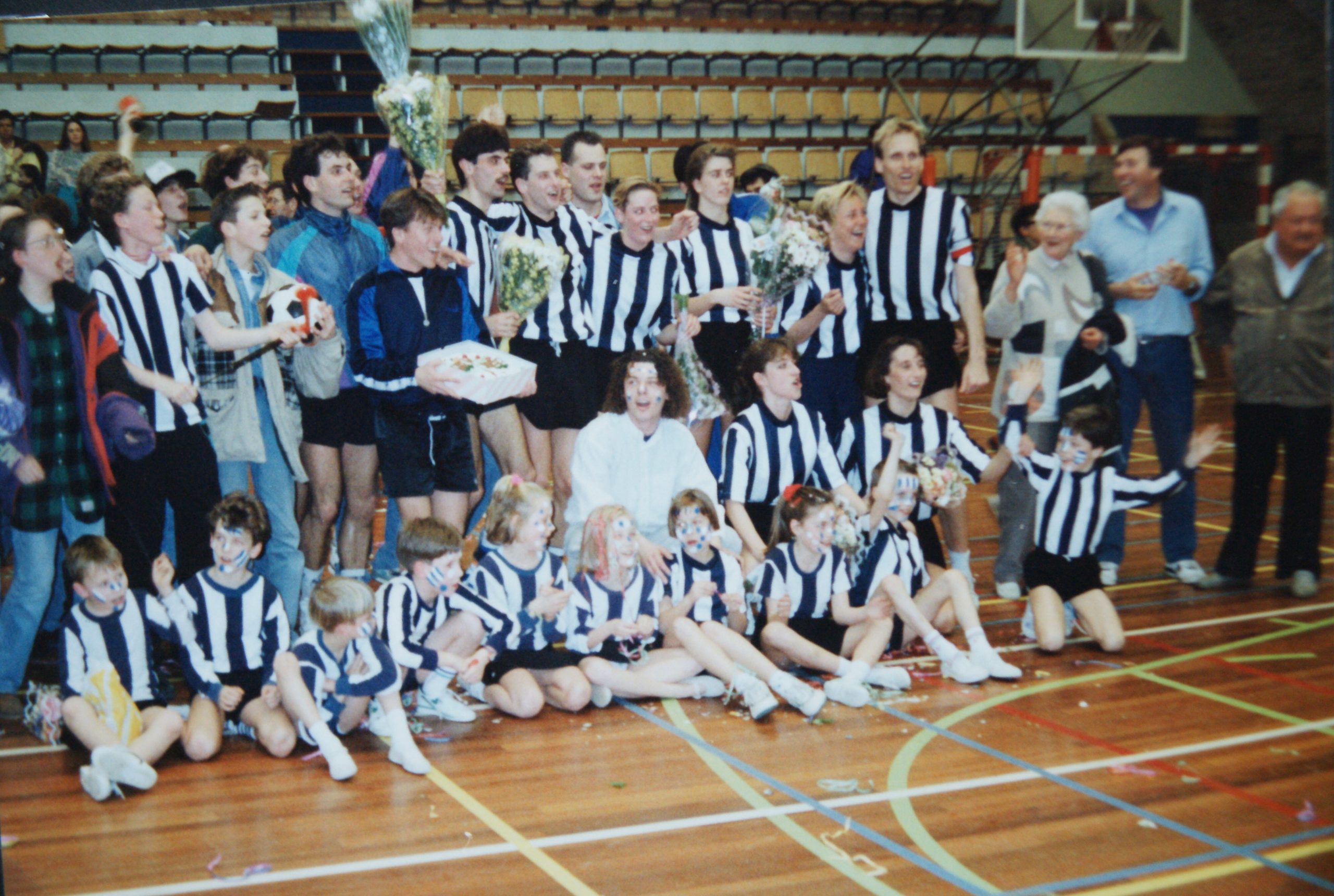Spelers, jeugdleden en supporters vieren samen feest in de sporthal.