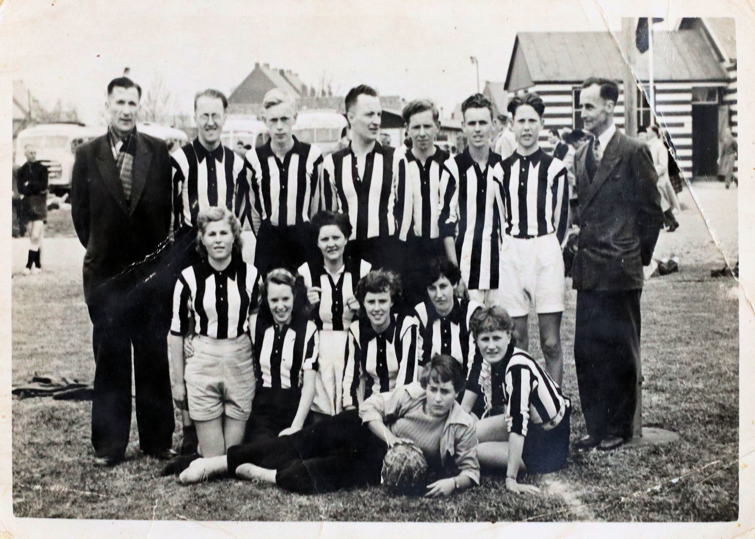 Een gemengd Animo-team poseert samen met twee begeleiders op het veld.