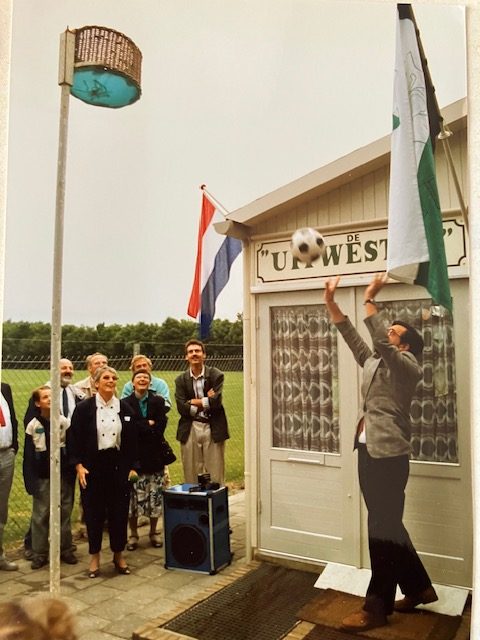 Bij het clubhuis wordt een bal naar de korf gegooid tijdens een bijeenkomst.
