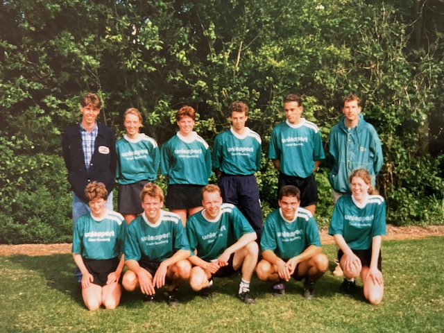Een gemengd Zuidwesters-team in groene shirts poseert op het grasveld.